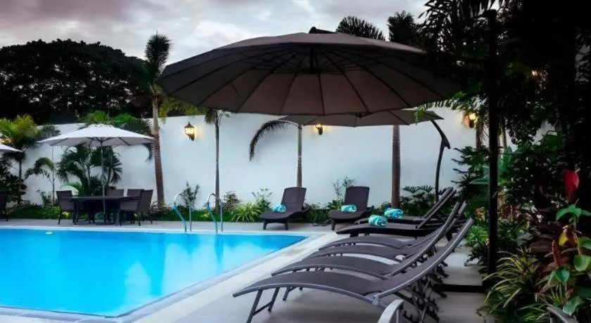 Pool with loungers and umbrella at Ipil Suites